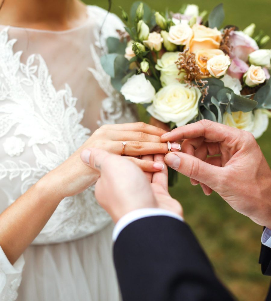 Wedding engagement rings. Groom put a ring on finger of his lovely wife. Concept wedding details. Happy family.