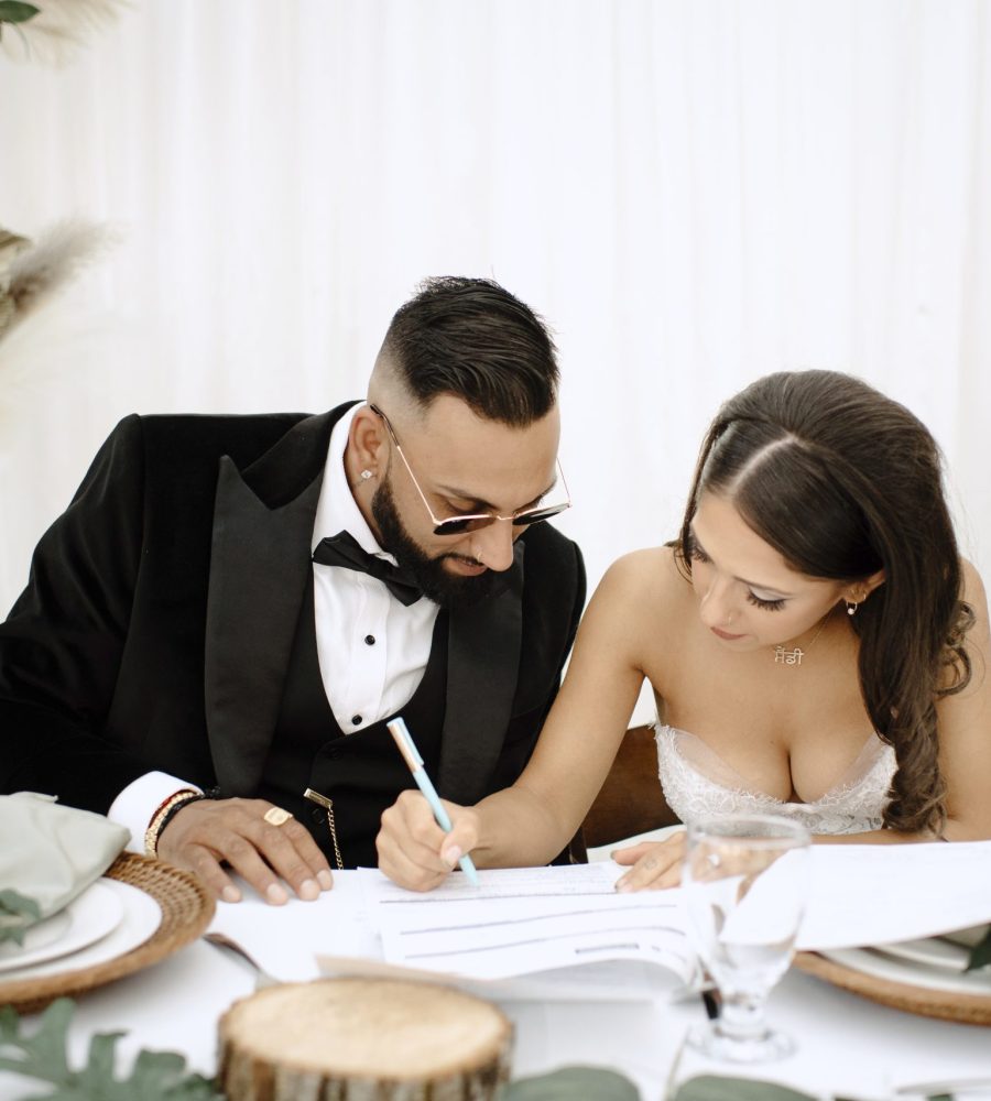 Bride and groom signing marriage documents at their wedding reception.