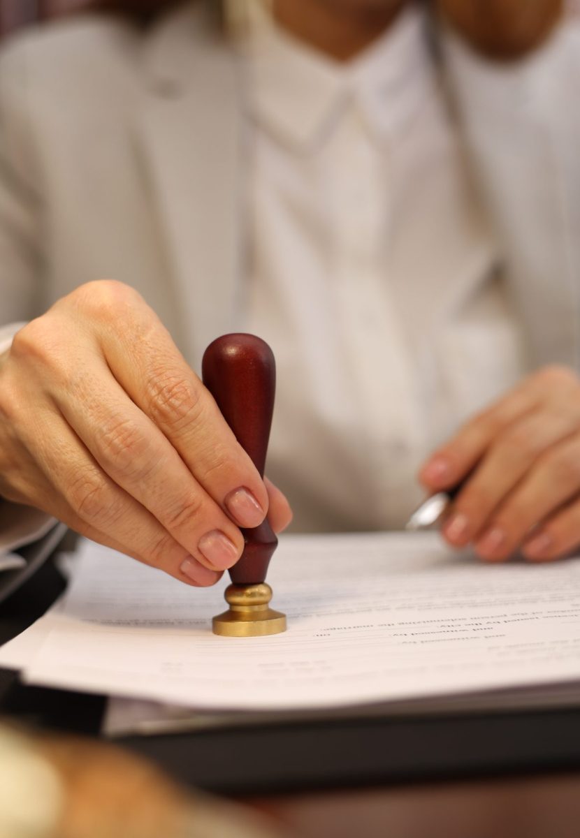 Notary stamping document at table in office, selective focus